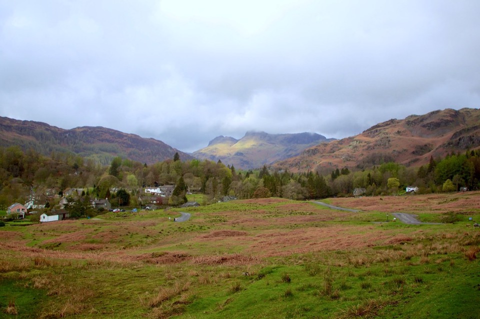 The village of Elterwater in Cumbria seen across open ground below the fells